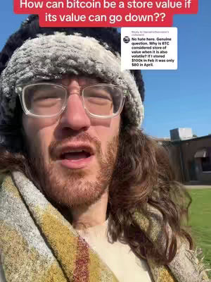 A man with long hair and a beard wearing glasses and a winter hat, looking towards the camera. Text overlays the image in red saying, "How can bitcoin be a store value if its value can go down??" A comment is visible in a white box, including question and answer.