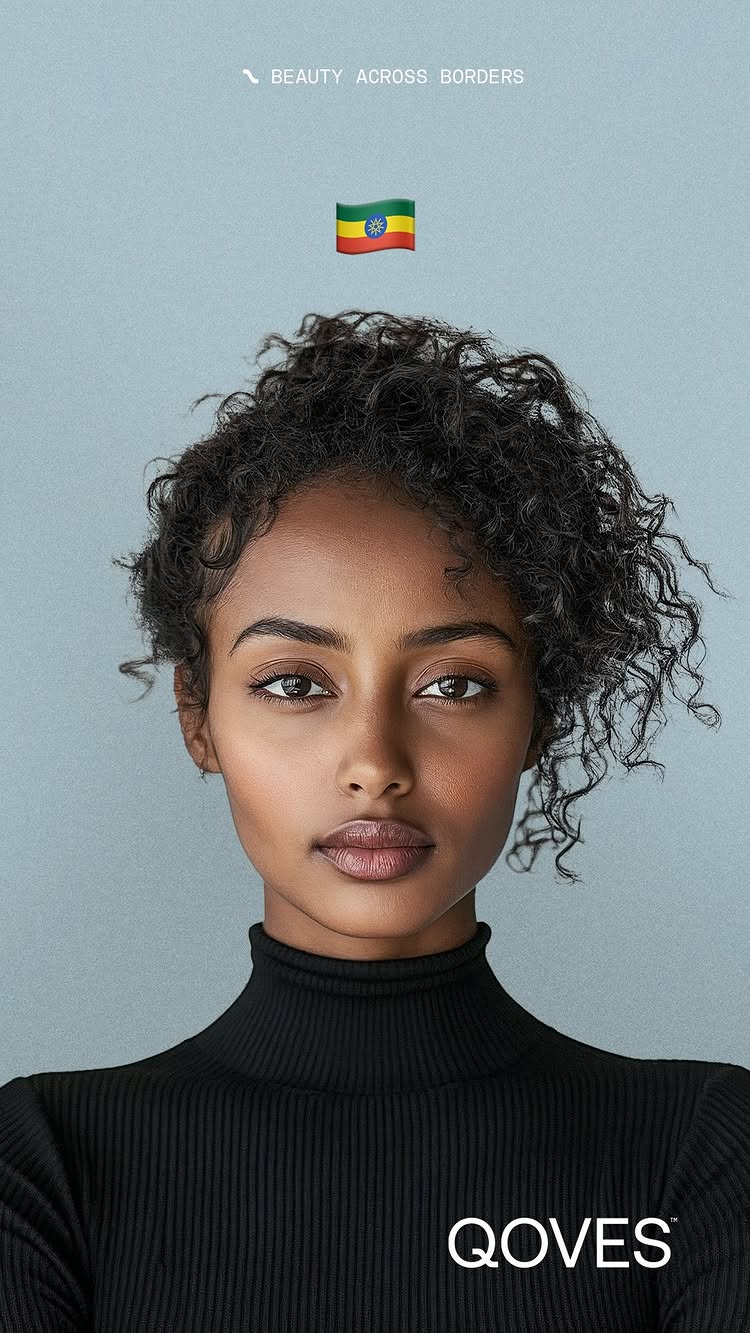 A studio portrait features a woman with brown skin and curly dark hair. Her eyes are open and she is looking directly at the viewer. The background is a muted blue-gray. She wears a black turtleneck. Text above reads 'BEAUTY ACROSS BORDERS' and an Ethiopian flag emoji