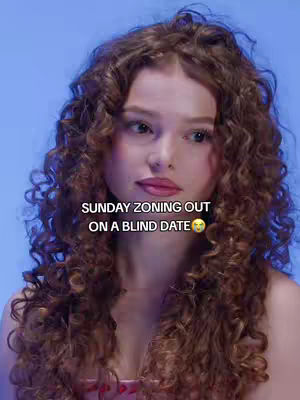 A young woman with long, curly brown hair looks slightly to the side, with a subtle expression. Text overlayed on the image reads, "SUNDAY ZONING OUT ON A BLIND DATE" with a concerned emoji.