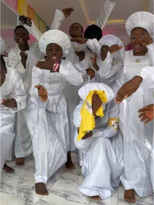 A group of people, likely in a religious setting, are wearing white garments. One individual, in the center, is highlighted with an open mouth. The composition is filled with the people, with some facing the camera and others in the background.