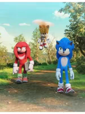 The image features three animated characters from the Sonic the Hedgehog movie franchise standing on a path in a park-like setting . Sonic, a blue anthropomorphic hedgehog, stands on the right. Knuckles, an echidna, in his signature red color and holding a book, is to the left. Tails, a fox, is floating in the air in the center. The background includes trees and a light blue sky.