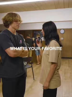 Two people in an indoor setting, one holding a phone, prompting each other. Overhead text that says, What is your favorite.