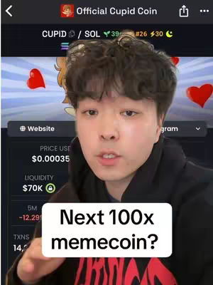 A selfie-style video featuring a young Asian man as the central figure. He is positioned in front of a blurred background that appears to be a website or app interface related to cryptocurrency, displaying data and charts. He is wearing a black hoodie and is looking directly at the camera. A text overlay is positioned at the bottom, and the overall composition suggests a focus on cryptocurrency trading and investment.