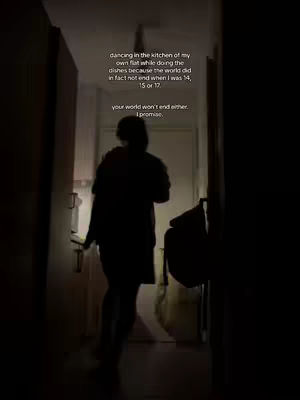 A silhouette of a person in a dimly lit hallway, walking towards a light source. The person is wearing clothing that obscures the body shape, the lighting is low-key, emphasizing the contrast between light and shadow. Text is added in the image.