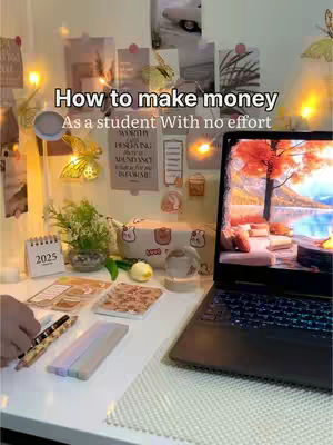 A desk setup with a laptop, notebooks, and decorations. The laptop screen shows a cozy, inviting scene. The wall behind the desk is adorned with photos and notes. The lighting is warm and inviting.