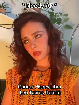 A woman with long brown hair and rosy cheeks is the central focus, set against a soft, warm-toned background. She wears an orange knit top and has makeup that accentuates her eyes and lips. Text overlays, with one at the top with a star, and another with the zodiac sign names, are added to the image.