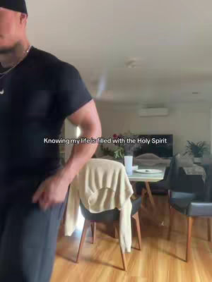 A man in a black t-shirt stands in front of a dining area; text overlayed across the image.
