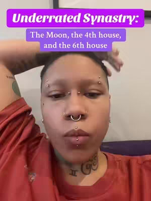 A close-up shot of a person with multiple facial piercings and tattoos, looking slightly upward with a neutral expression. The person is wearing a red shirt, and a purple banner with white text overlays their head, which reads "Underrated Synastry: The Moon, the 4th house, and the 6th house."