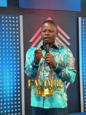A man in a patterned turquoise shirt is speaking into a microphone. Overlaid on the image are the words "FAVOUR" in gold with a gold crown image below.