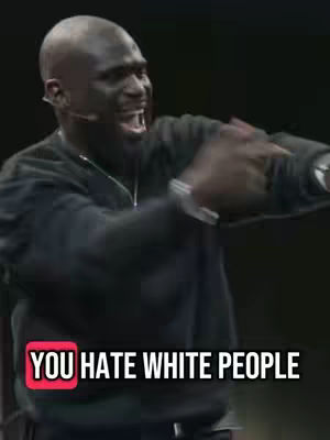 A man with a shaved head is speaking into a microphone with an emotional facial expression. Text overlaid reads 'YOU HATE WHITE PEOPLE'.