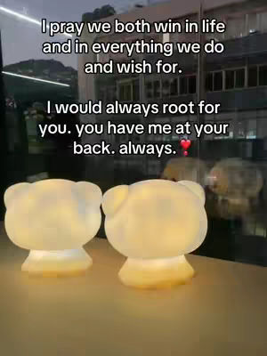 The image features two glowing bear-shaped lamps on a surface, likely a table. The setting appears to be indoors, with the background blurred, suggesting a focus on the lamps. Text overlayed on the image includes a supportive message, framed by a dark sky and a lit interiors background.