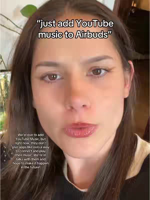A selfie-style shot featuring a woman with brown hair and eyes. The background is slightly blurred, with hints of foliage and interior elements. The image is framed to focus on her face, and the dominant color scheme is warm tones due to the skin and ambient lighting, with text in white