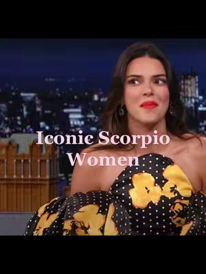 The video cover features a woman with long, dark hair sitting in front of a background with a blurry cityscape. Across the image, text reads 'Iconic Scorpio Women'. The woman has red lipstick and is wearing a black dress with yellow floral patterns.