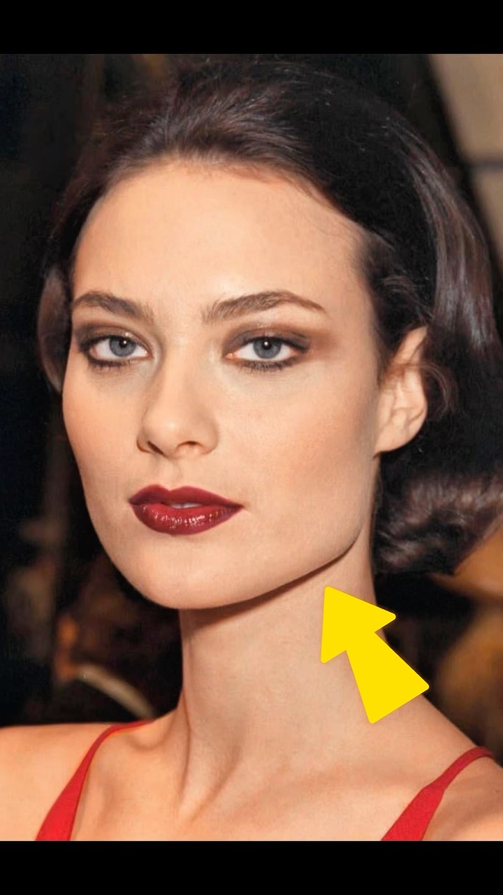 The cover image features a close-up of a woman's face, with a focus on her features and the arrow pointing to her jawline. She has dark hair, dark eye makeup, and deep red lipstick. The lighting appears to be soft, and the background is blurred, drawing attention to her face. The arrow is yellow.
