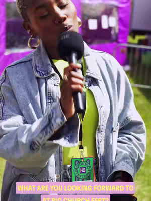 A person with short, curly hair and hoop earrings holds a microphone and speaks. They wear a denim jacket over a neon green top. A badge hangs on their neck, and the background is a blurry outdoor setting. Text overlaid at the bottom reads, "WHAT ARE YOU LOOKING FORWARD TO AT BIG CHURCH FEST?"
