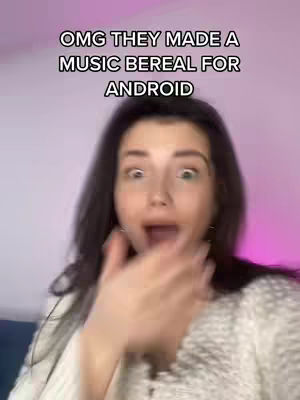 A young woman with dark hair is the central focus, her face expressing surprise with wide eyes and an open mouth. The background fades out to a pinkish hue, and the text overlayed at the top, "OMG THEY MADE A MUSIC BEREAL FOR ANDROID", is in a bold sans-serif font to draw attention.