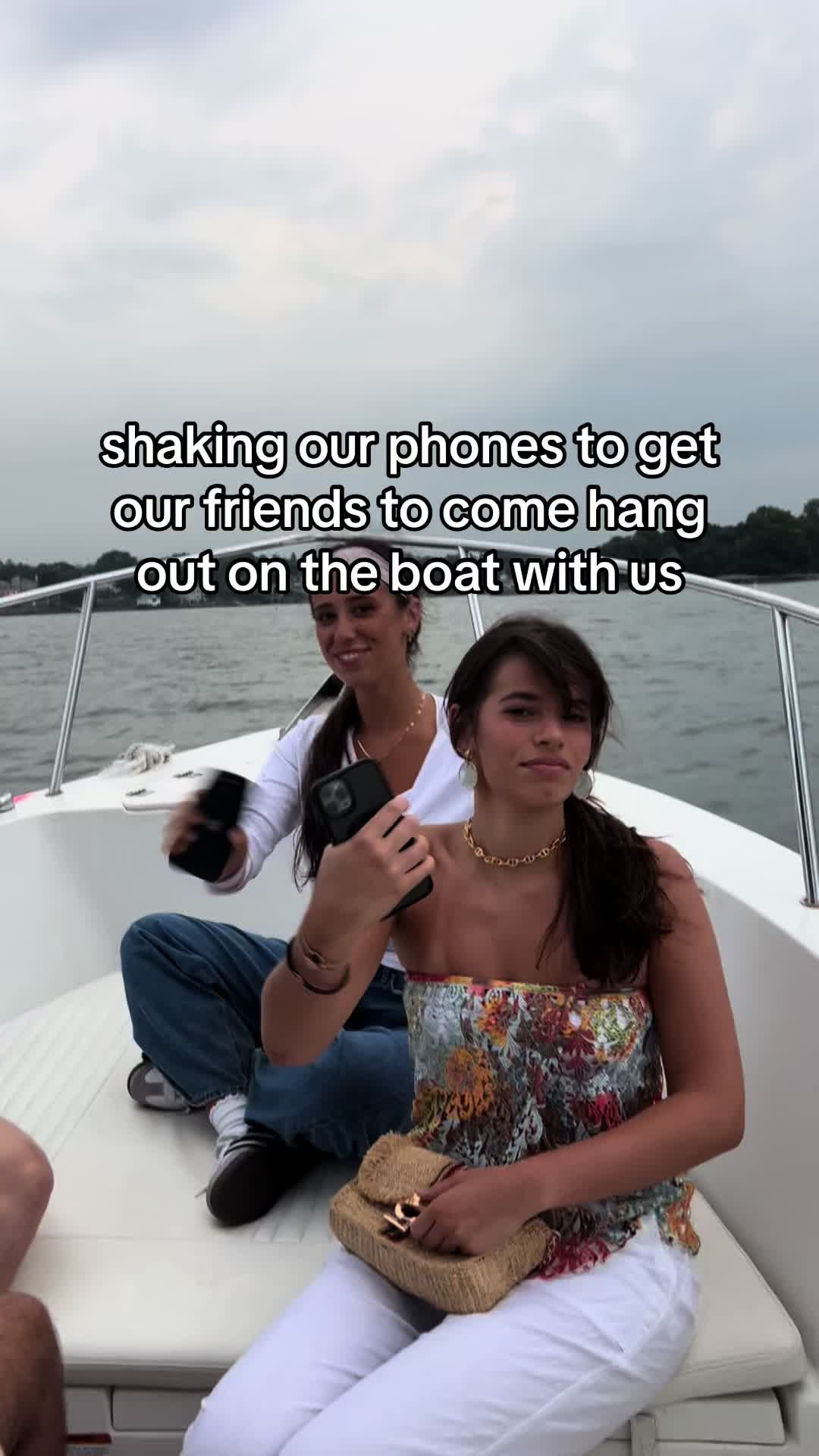 Two young women are seated on a white boat, smiling. The background shows a cloudy sky and water. Text overlays the image.