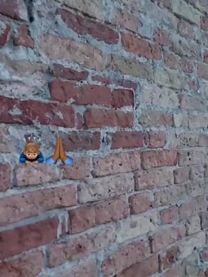 An image of a red-brick wall provides the backdrop. Two emoji are placed on the wall, one representing a person and another representing hands in prayer.