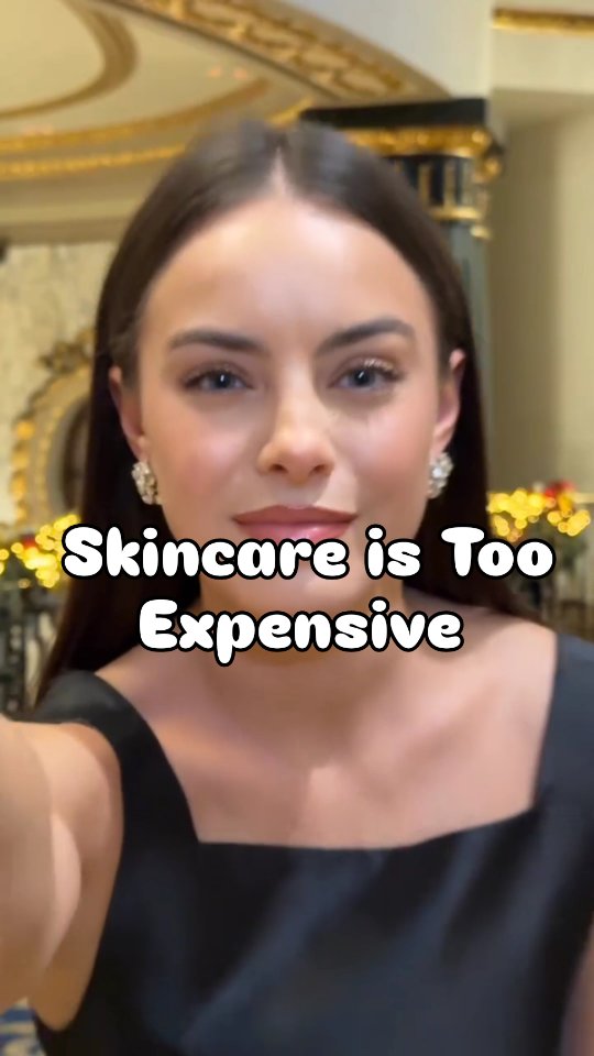A woman with a dark dress, visible earrings, and a neutral expression. The background is out of focus, but gives the impression of a luxurous space with decorative elements. The overlayed text is stylized in white.
