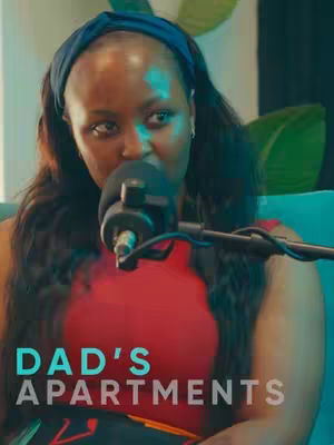 A woman with dark hair and a blue headband is speaking into a microphone. The backdrop is a soft teal, with a segment of green plant visible on the top right. Bold, white text stating "DAD'S APARTMENTS" is overlaid over the lower portion of the image, near the girl's torso.