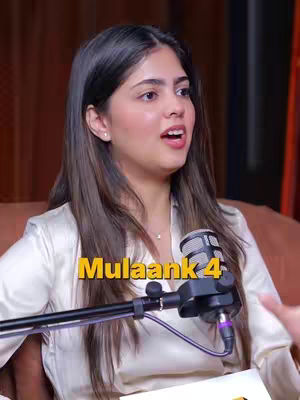 A woman is seated in a studio setting, facing slightly left with an open mouth as if speaking. A microphone is positioned in front of her, and the text overlay "Mulaank 4" is placed over the image. The background is a blurred, warm-toned area with brown and orange hues