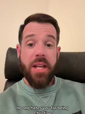 A man with a beard is centered in the frame, speaking directly towards the viewer. Text overlayed on the bottom states 'no one hates you for being Christian.' The background softens to a neutral tone, highlighting the man.