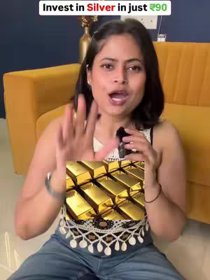 A woman is holding a simulated gold bar in front of a backdrop. She is wearing a white top with intricate lace and dark denim jeans. The background features an indoor setting with a yellow couch. Text overlaid on the top indicates an investment opportunity with the sum. 