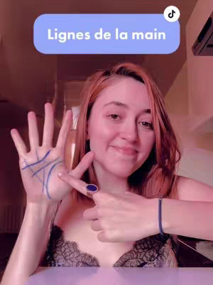 The cover image shows a woman with red hair. She is smiling and holding up her left hand, which has blue lines drawn on it, as if to show the lines of the palm. She is pointing to this palm with her right index finger, which is adorned with a blue ring. The background appears to be a home, possibly a room with warm lighting, and has a logo for TikTok over the image. The color palette is dominated by warm tones.