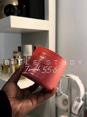 The cover image shows a person's hand holding a pink candle, which is placed in front of a white shelf. The candle is the focal point, with text overlaid that reads Bible Study, Isaiah 55:6. In the background, there are shelves with various items, including bottles and a pair of white headphones.
