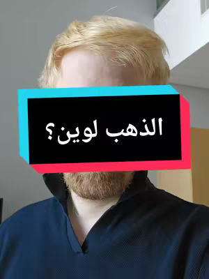 A selfie-style shot featuring a man's face, partially obscured by a color block. The man has light blond hair and a ginger beard. The color block across his face contains text in Arabic.