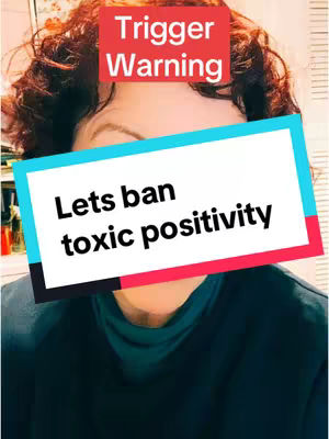 A selfie with a woman's face partially obscured by overlay text. The woman has curly red hair. A red rectangle with the text 'Trigger Warning' is above her face. A rectangular text box with a teal background and white text covers part of her face, displaying 'Lets ban toxic positivity'.