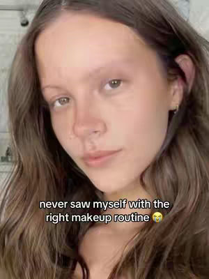 A close-up selfie of a person, featuring a brown haired person, looking directly at the camera with a neutral expression. The text overlay below the person read, "never saw myself with the right makeup routine 🥺", with a blurred background.