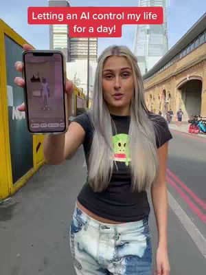 A woman with long, silver hair stands outdoors, holding a phone displaying an app on its screen. Text above her reads 'Letting an AI control my life for a day!'. The setting appears to be a city street with buildings and pedestrians in the background.