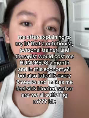 A selfie-style video with the creator in the center frame. She has dark hair and fair skin. Text overlays her, written in a sans-serif font. The background is a blurry interior, with a light fixture.