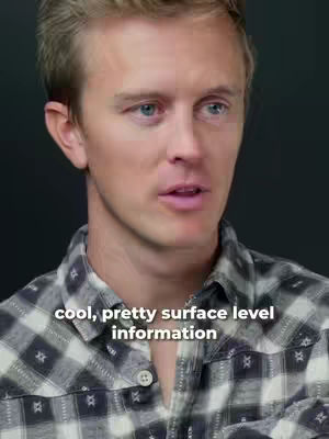 A medium shot features a fair-skinned man with short, light brown hair and blue eyes. He's wearing a black and white plaid shirt. Overlaid at the bottom is white text.