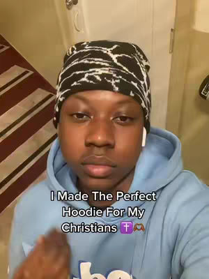 A young man with dark skin and a black and white patterned beanie is the focus. He's wearing a light blue hoodie and has white earbuds in. Text overlayed in the image reads, 'I Made The Perfect Hoodie For My Christians' with emojis.