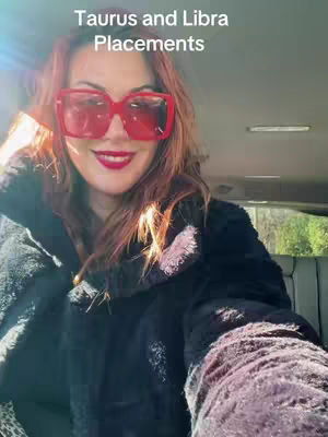 A woman wearing large red sunglasses and a black coat is seated inside a car. The text "Taurus and Libra Placements" is overlaid on the image. The overall shot is a selfie-style photograph.