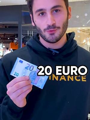 A man with a beard, wearing a black hoodie, holds up a 20 Euro bill. White text overlays the image, in a two-tone font with contrasting black outline, and the Binance logo is at the bottom.