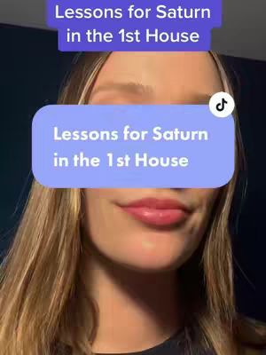 A close-up shot features a woman with long blonde hair, focusing on her face with a light blue rectangle overlay covering her nose. The text overlay states 'Lessons for Saturn in the 1st House' in white letters, and is also featured at the top in a darker color. The image is framed as a portrait, and the woman is smiling below the text elements.