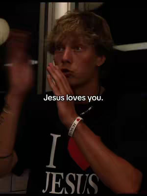 A young man with light brown hair is speaking, holding his hands up. The text overlay reads: Jesus loves you.