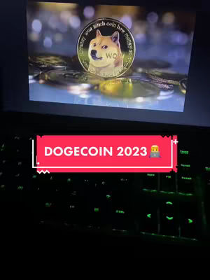 A video featuring a computer screen displaying a Dogecoin coin resting on a pile of other coins. The screen is positioned above a lit-up keyboard.
