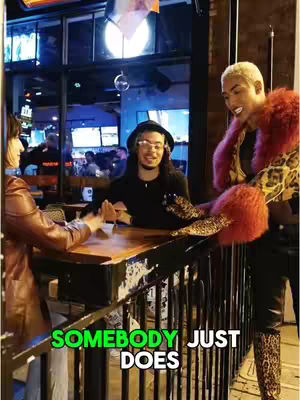 The cover image shows a scene in a bar with three people. The focus is on a person on a wooden table with two other people next to them. Text overlays exist on the bottom of the image.