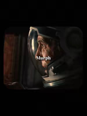The image is a film still with a black frame. The main focus is on a man's face in profile, wearing a silver space helmet. The word 'Murph' is written in white. The background is dark.