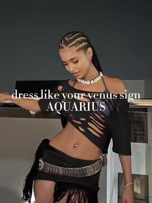 A vertical video cover image featuring a woman posing with one arm extended, with text overlays. She has braided hair and wears a black top with cutouts, a skirt, and jewelry. The background is a dark, indoor setting.