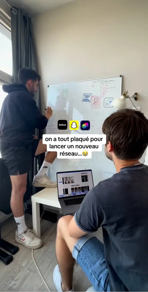 Two young men are in a room interacting in front of a whiteboard. One man is writing on the whiteboard, and the other is seated in front of a laptop. The whiteboard has some drawings and notes along with social media icons. Text overlays describe the scene.