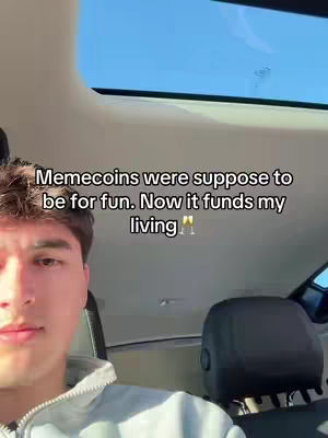 A selfie-style shot taken inside a car. The creator is a young man with short brown hair, framed from the chest up, his face occupying the left side of the image. The sky is blue and visible through the car's sunroof. Text overlayed on the image states: "Memecoins were suppose to be for fun. Now it funds my living".