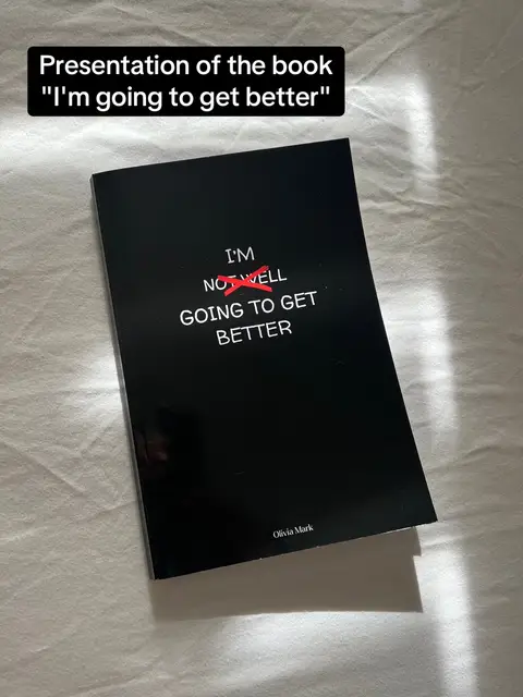 A book with a black cover is displayed on a white surface, likely a bed. The book title, "I'm going to get better," is prominently displayed in white text, with the "NOT" in "I'M NOT WELL" crossed out in red. Overlayed text at the top announces "Presentation of the book "I'm going to get better"". A shadow from a nearby light source casts across the book. The author's name ,"Olivia Mark" is faintly visible at the bottom.