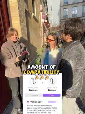 The image captures a street setting with three individuals. A woman on the left is center-focused and holding a phone. Two other people are to the right of the frame, one wearing sunglasses and anther wearing a leather jacket. The focus is on the woman in the middle as the background shows tall classical buildings characteristic of a city.