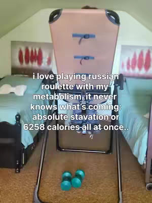 The image features an inversion table as the central focus, with an interior setting and two beds visible in the background. Text overlays are present on the image. Several small blue dumbbells are at the bottom.