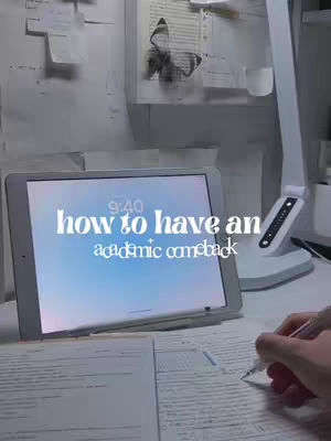 An organized desk with an open iPad displaying text that says "how to have an academic comeback." A hand with a pen is visible, writing on a piece of paper. The background includes a desk lamp, notes, and a decorative image of a butterfly.